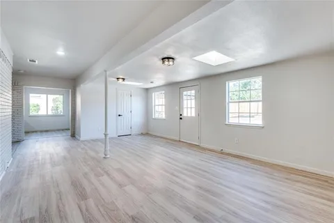 a view of an empty room with window and wooden floor