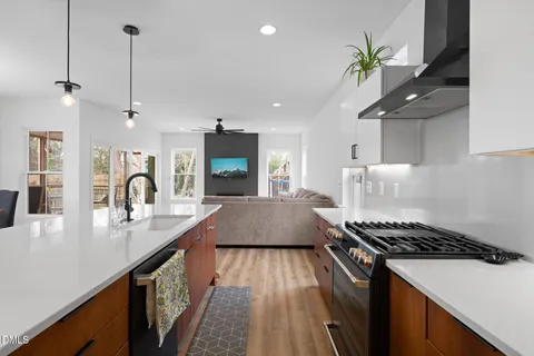 a large kitchen with stainless steel appliances kitchen island granite countertop a stove a refrigerator a sink dishwasher and white cabinets with wooden floor