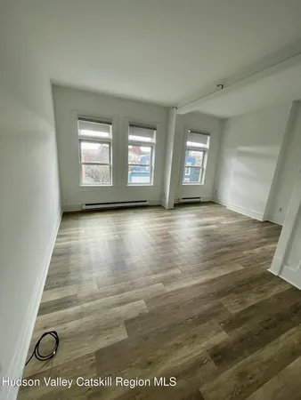 an empty room with wooden floor and windows