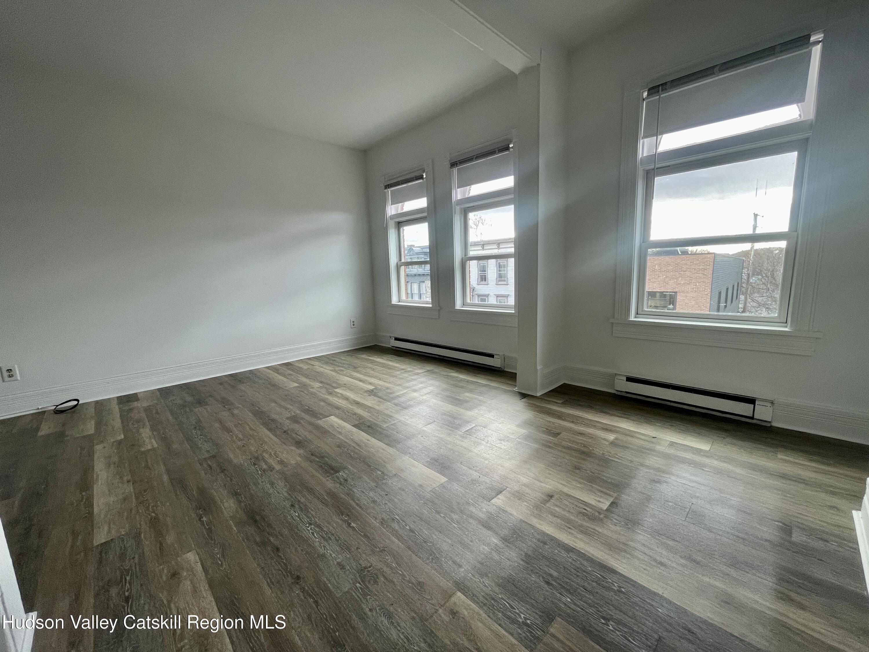 426 Warren Street, Unit 3 Hudson, NY 12534 - Photo 7 of 13 an empty room with wooden floor and windows