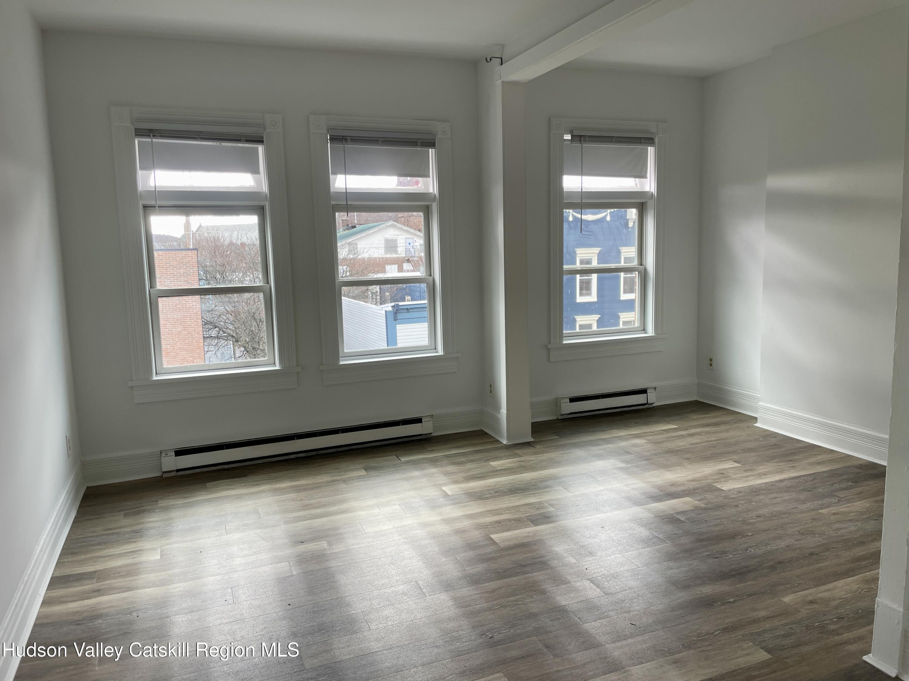 426 Warren Street, Unit 3 Hudson, NY 12534 - Photo 8 of 13 an empty room with wooden floor and windows