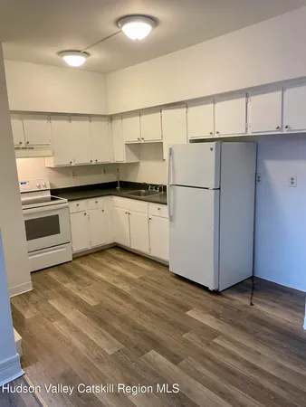 a view of a hallway with wooden floor and a sink