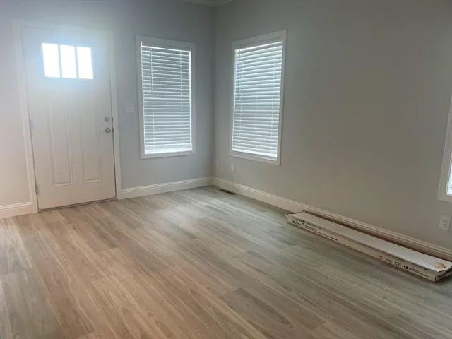 a view of an empty room with wooden floor and a window