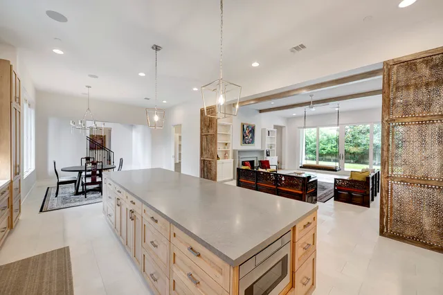 a kitchen with stainless steel appliances a stove a sink a refrigerator a couch and a larger window