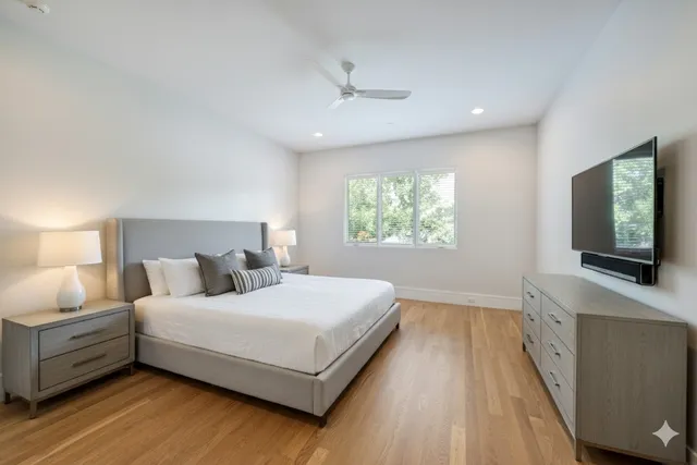 a bedroom with a large bed and a flat tv screen on dresser