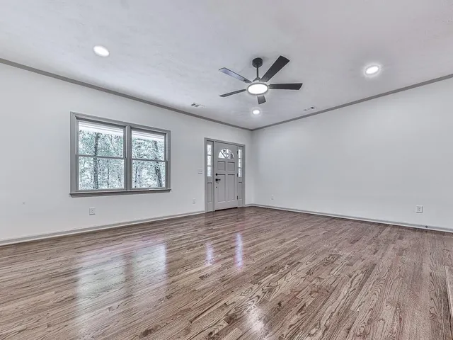 a view of an empty room with a window and wooden floor