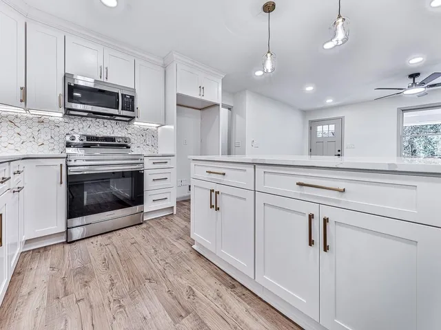 a kitchen with white cabinets stainless steel appliances and wooden floor