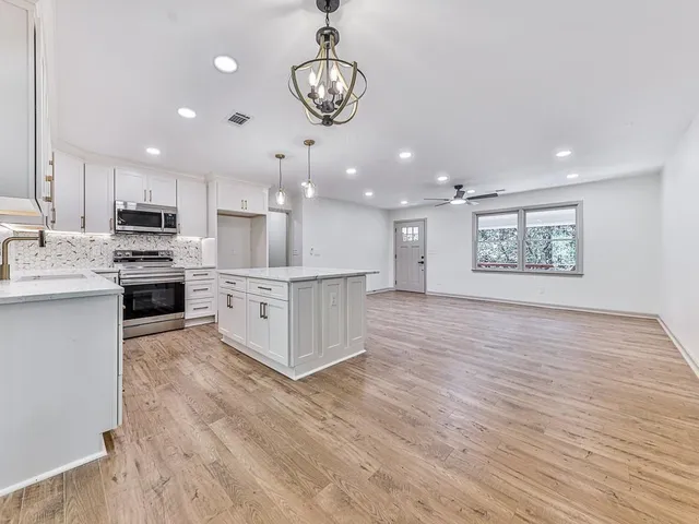 a large kitchen with stainless steel appliances kitchen island a large counter top and wooden floors