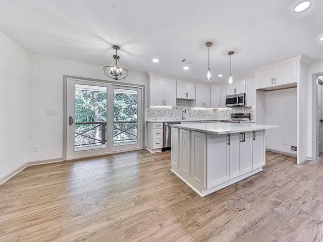 a kitchen with stainless steel appliances granite countertop a stove top oven a refrigerator a sink with island and wooden floor