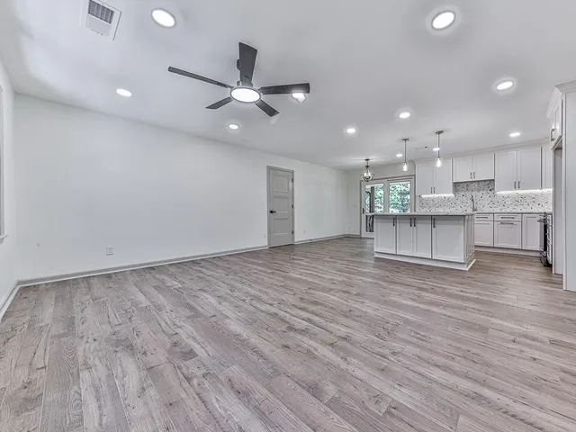 a view of a kitchen with kitchen island wooden floors appliances and a ceiling fan