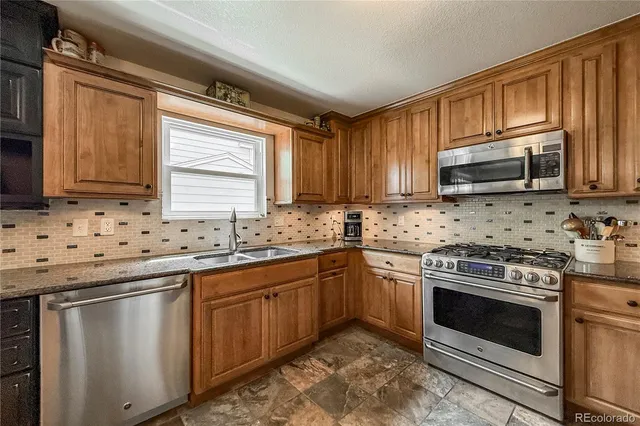 a kitchen with granite countertop a sink stove and microwave