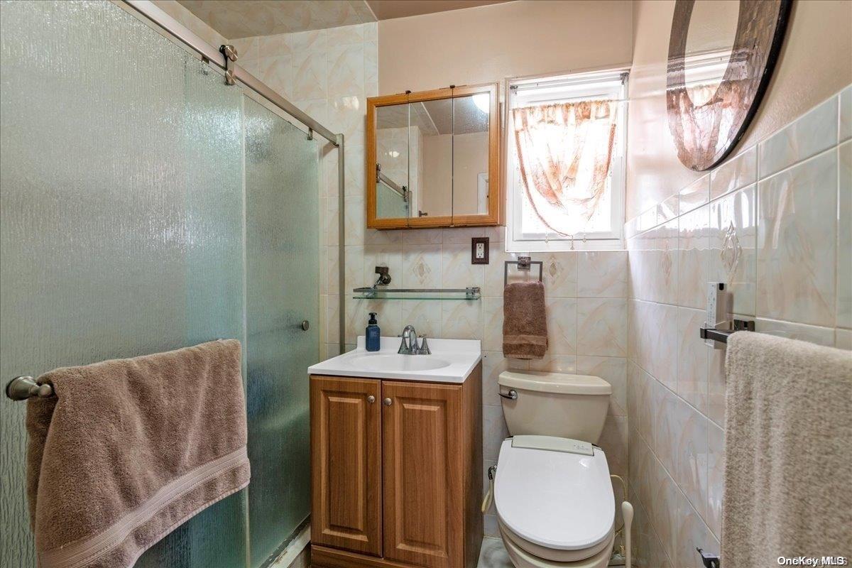 91-26 79th Street Queens, NY 11421 - Photo 13 of 20 a bathroom with a toilet sink vanity shower and mirror
