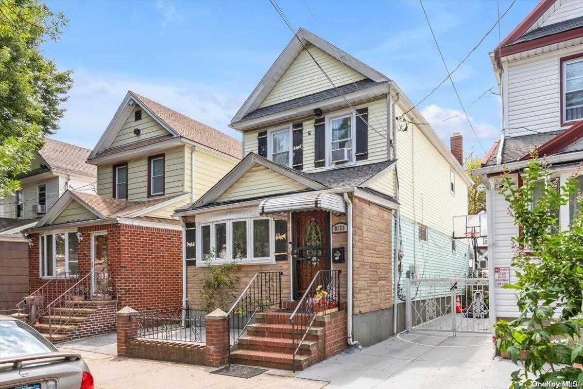91-26 79th Street Queens, NY 11421 - Photo 17 of 20 a view of a white house with large windows and a small yard