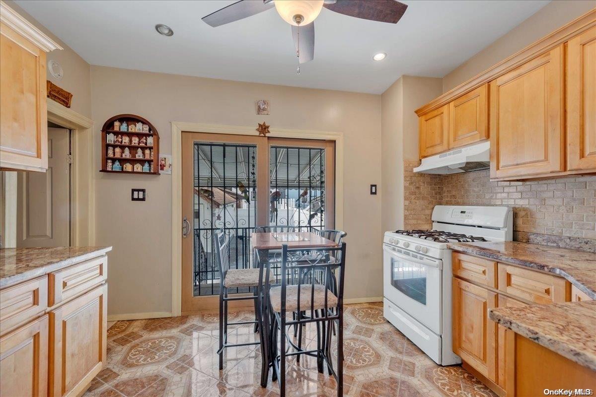 91-26 79th Street Queens, NY 11421 - Photo 7 of 20 a kitchen with stainless steel appliances granite countertop a stove a refrigerator a sink a dining table and chairs with wooden floor