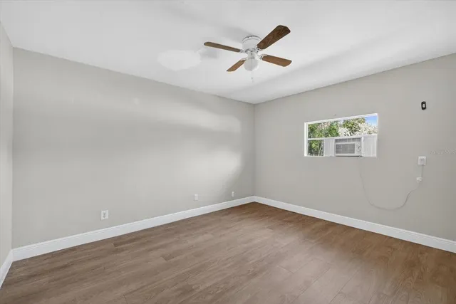 an empty room with wooden floor and a ceiling fan