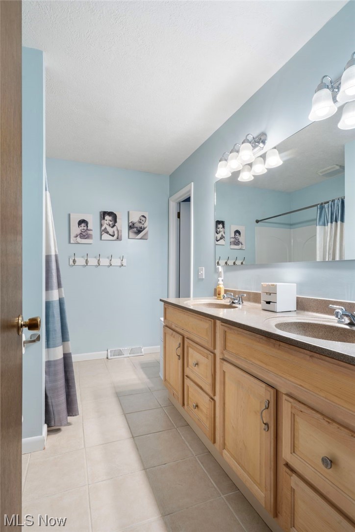 801 Netherwood Avenue Northwest Canton, OH 44708 - Photo 15 of 44 Bathroom featuring double vanity, a textured ceiling, tile flooring and second door to the master bedroom