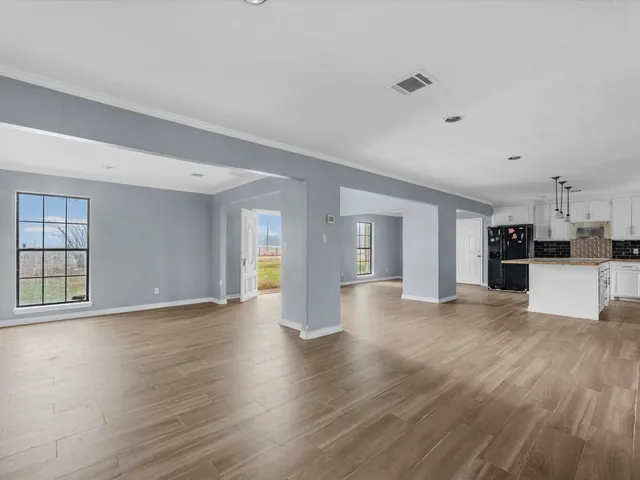 a large white kitchen with granite countertop a stove a sink and white cabinets