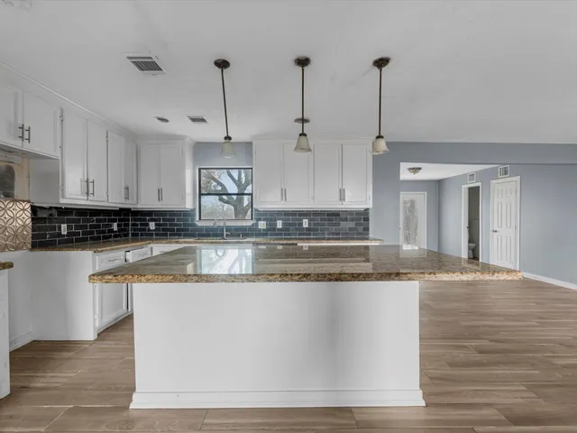 a kitchen with kitchen island granite countertop a sink a counter space appliances and cabinets