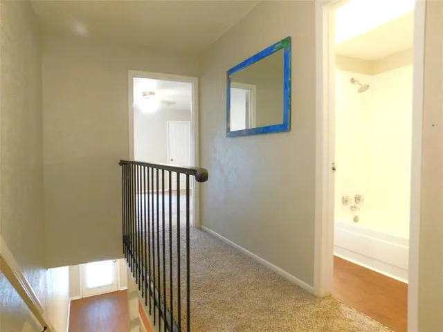a view of a hallway with wooden floor and a bathroom