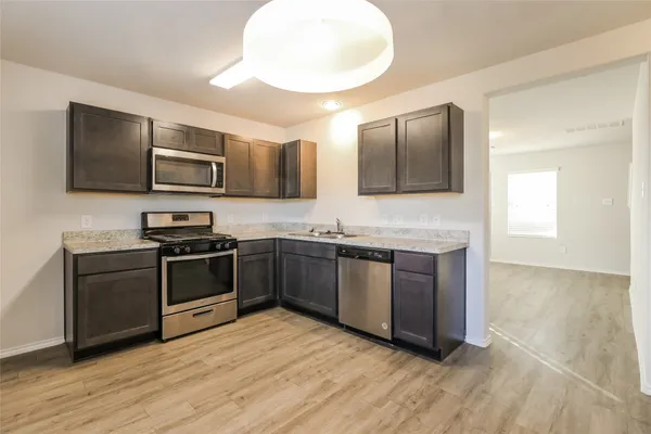 a kitchen with stainless steel appliances kitchen island granite countertop a stove a sink and a microwave