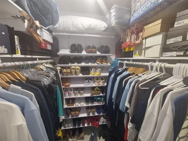 a view of walk in closet with clothes and shoes