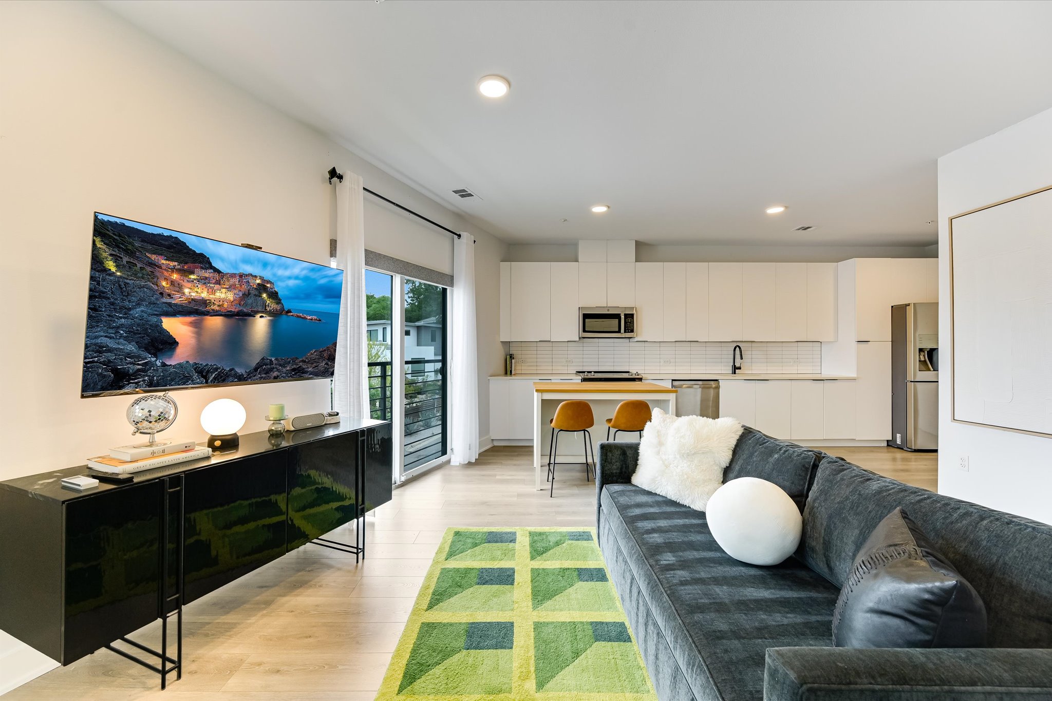 Open-concept living area featuring light wood-finish flooring, recessed lighting, and a contemporary kitchen