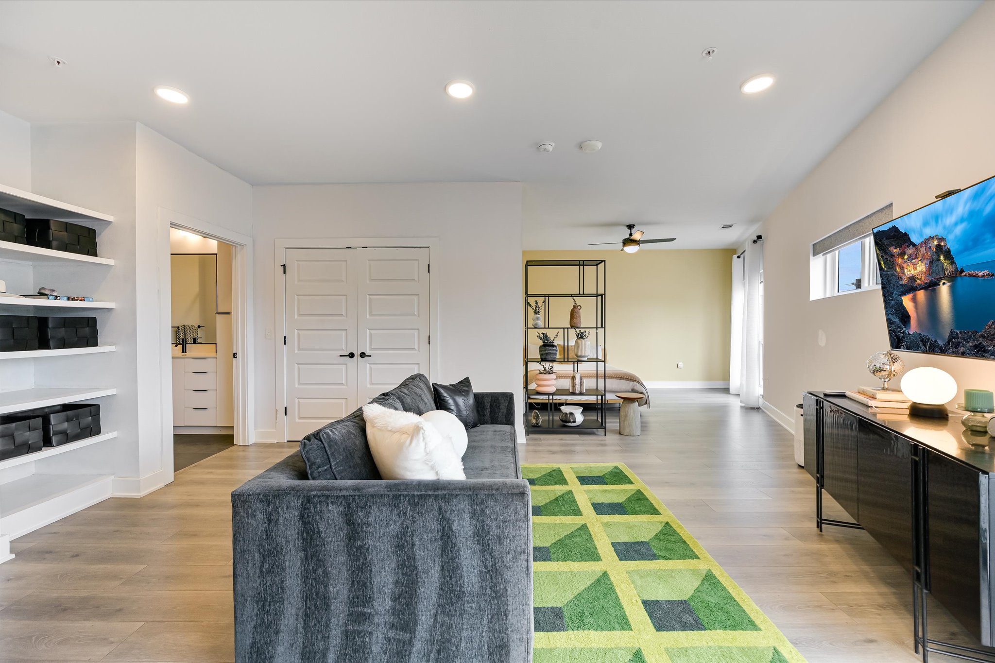2220 Webberville Road, Unit 308 Austin, TX 78702 - Photo 2 of 21 Open-concept living area featuring light wood-finish flooring, recessed lighting, built-in shelving, and a wall-mounted television