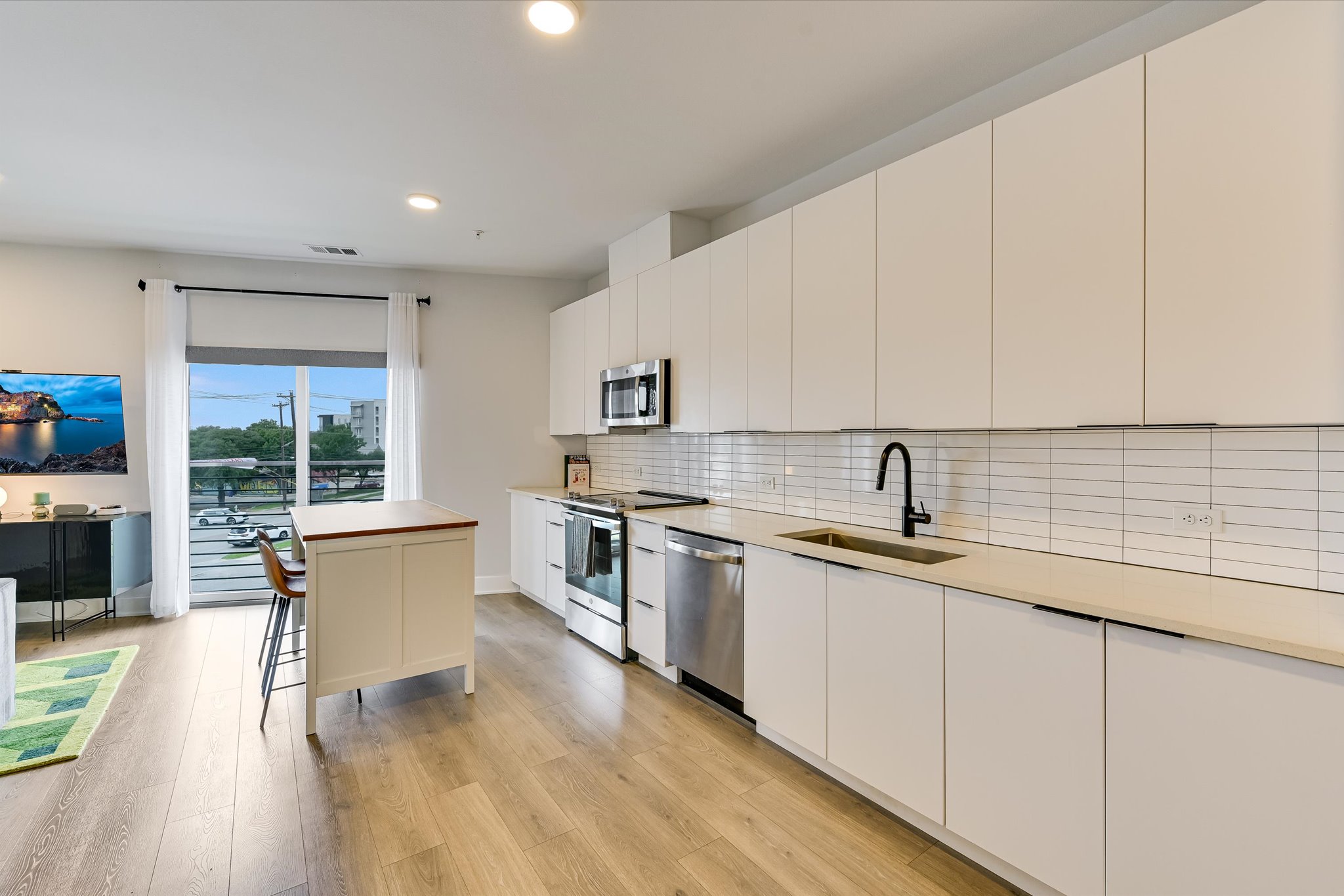 2220 Webberville Road, Unit 308 Austin, TX 78702 - Photo 4 of 21 Modern kitchen featuring slab-front white cabinetry, a light-toned countertop, and stainless steel appliances