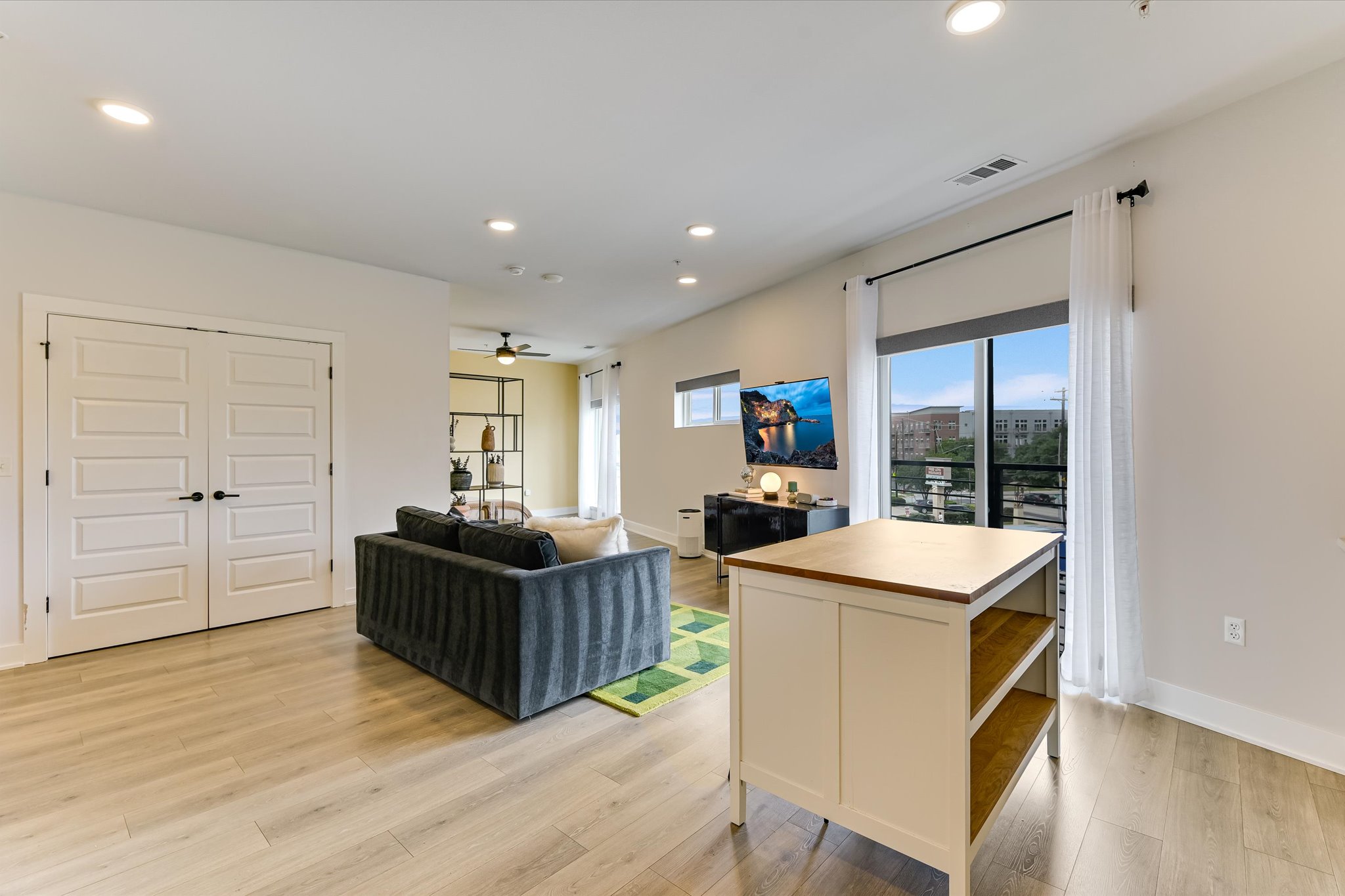 2220 Webberville Road, Unit 308 Austin, TX 78702 - Photo 8 of 21 Bright living area featuring wood-finish flooring, recessed lighting, and a sliding glass door opening to an exterior balcony