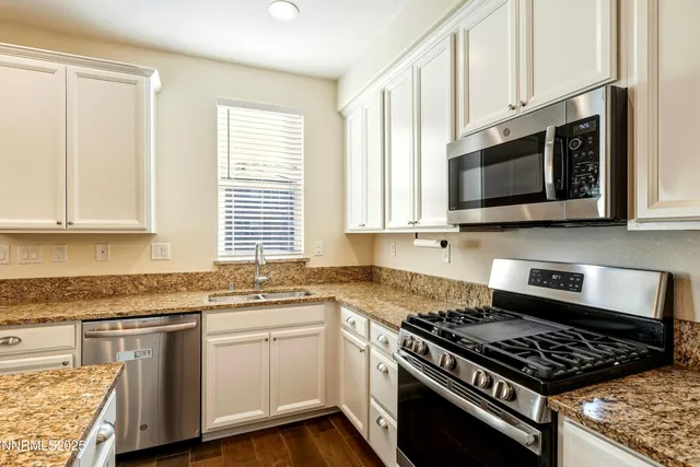 a kitchen with stainless steel appliances granite countertop white cabinets a stove top oven and granite counter tops