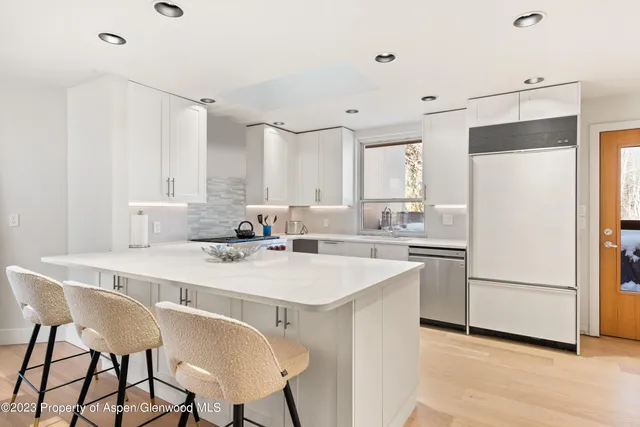 a kitchen with a sink a stove a refrigerator and white cabinets