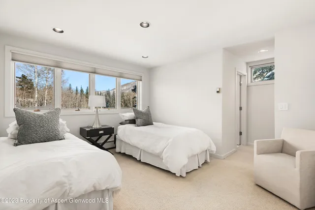 a bedroom with two beds and large window