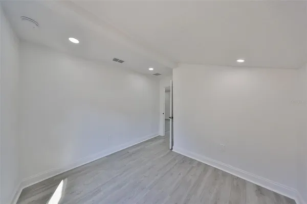 a view of an empty room with wooden floor and a ceiling fan