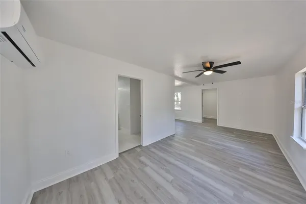 a view of an empty room with wooden floor and a ceiling fan