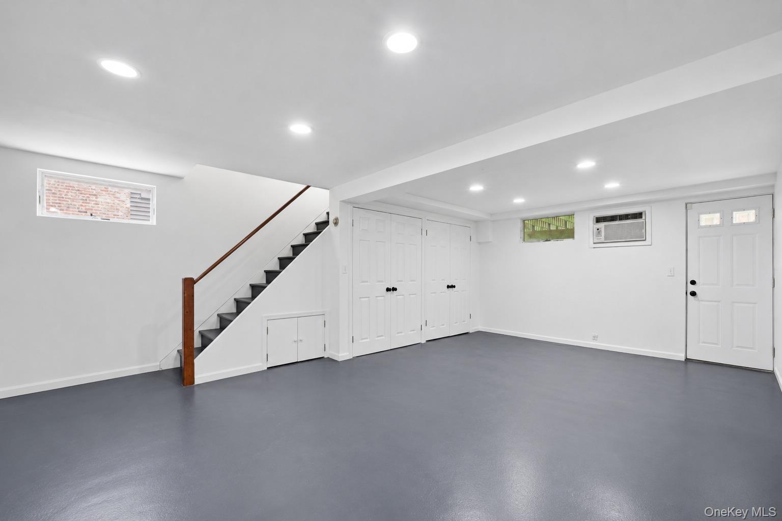 144 Bell Road Scarsdale, NY 10583 - Photo 32 of 49 Expansive basement-level space featuring recessed lighting, a finished staircase with wood handrail, multiple storage closets with bifold doors, and a paneled entry door