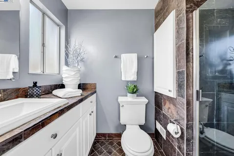 a bathroom with a granite countertop toilet sink and mirror