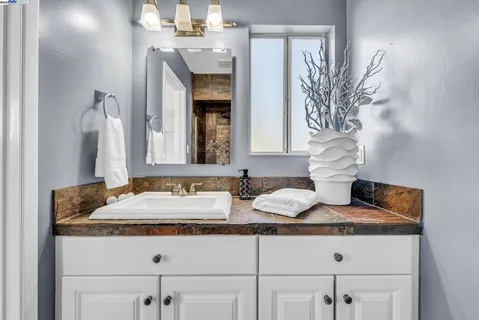 a bathroom with a granite countertop sink and a mirror