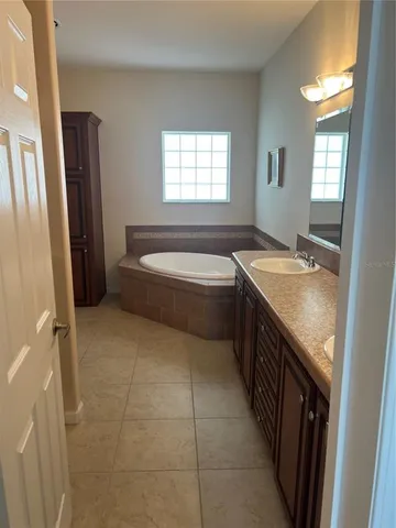 a spacious bathroom with a tub sink and mirror