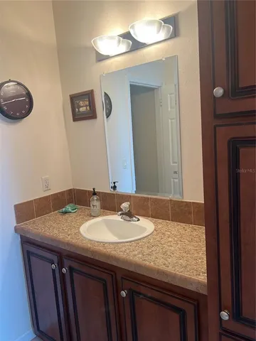 a bathroom with a granite countertop sink a mirror and wooden cabinets