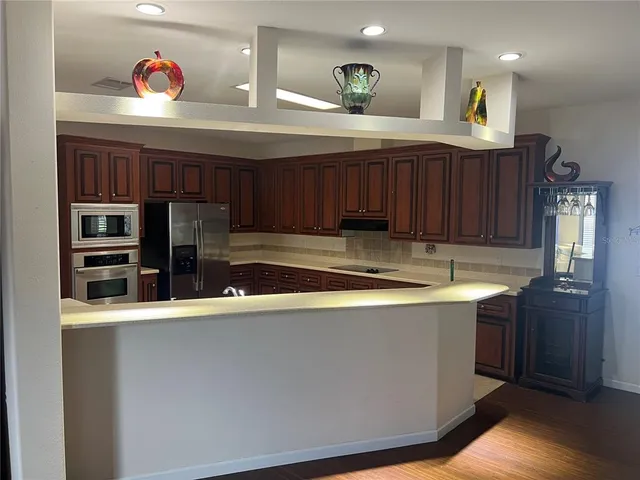 a kitchen with stainless steel appliances granite countertop a sink a stove and a wooden floors