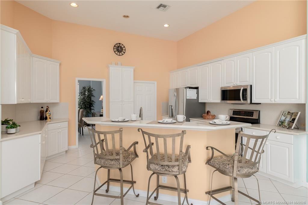 2216 Southeast Stonehaven Road Port St. Lucie, FL 34952 - Photo 12 of 67 a kitchen with stainless steel appliances a microwave a stove a table and chairs