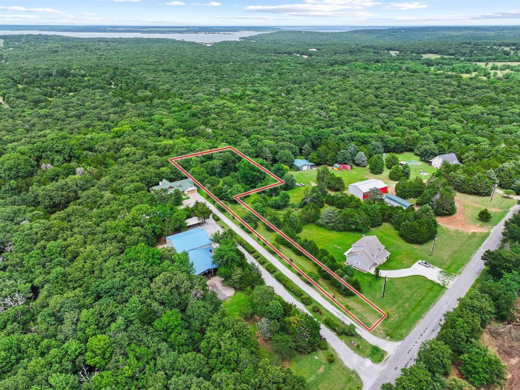 207 Paradise Park Road Pottsboro, TX 75076 - Photo 27 of 28 Aerial view of a sprawling property featuring extensive tree coverage, a defined parcel outline, and a visible roadway