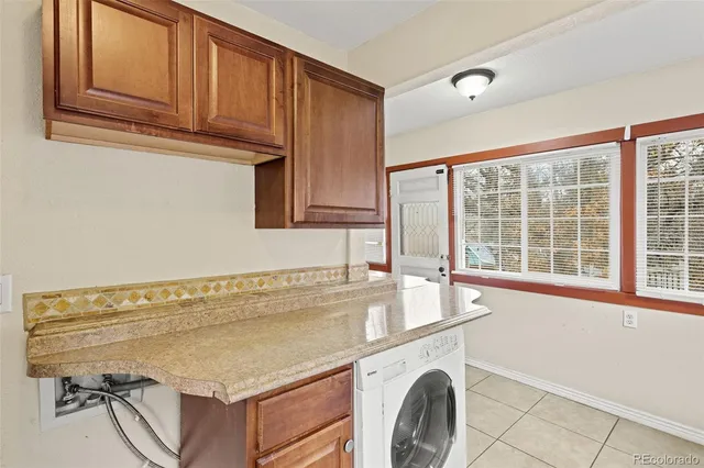 a utility room with stainless steel appliances granite countertop a sink and a wooden cabinets