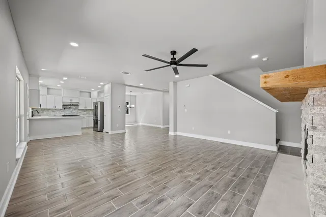 a view of a livingroom with a ceiling fan wooden floor and a ceiling fan