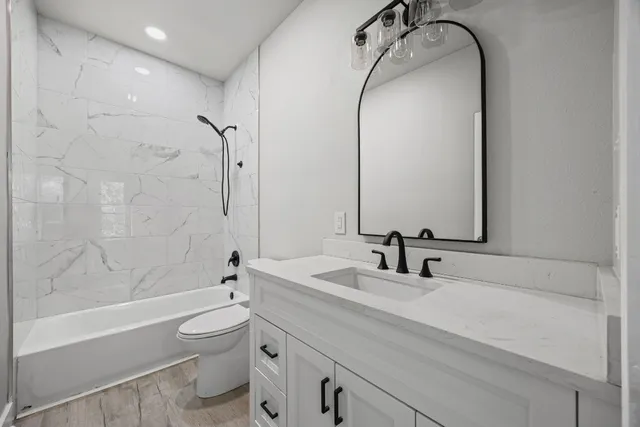 a bathroom with a granite countertop sink a toilet and a mirror