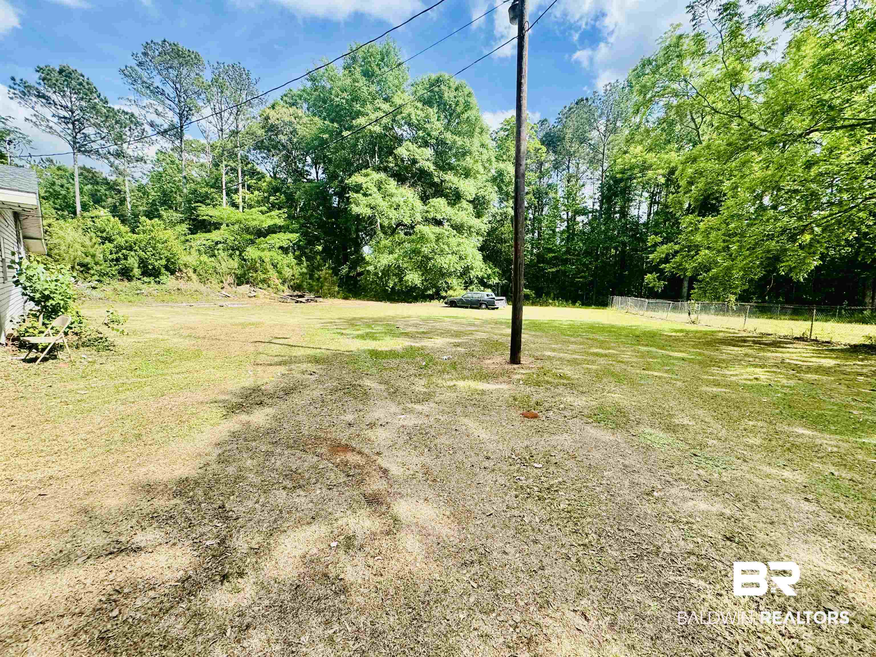 226 Elizabeth Street Evergreen, AL 36401 - Photo 8 of 35 Expansive outdoor space featuring a large grassy area, mature trees, and partial chain-link fencing