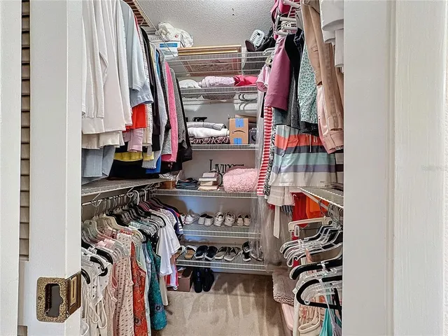 a view of walk in closet with clothes and shoes