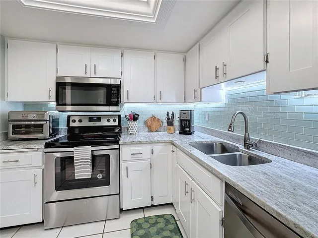 a kitchen with white cabinets a sink and appliances