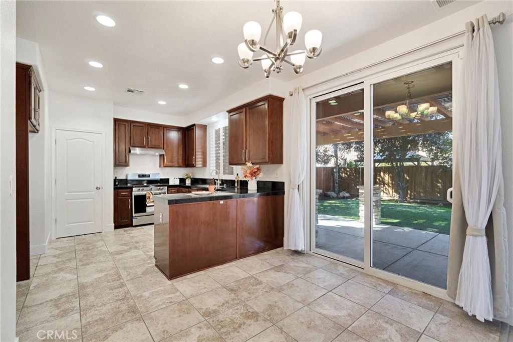 692 Blueberry Lane Madera, CA 93638 - Photo 12 of 44 a large kitchen with kitchen island a large window cabinets a sink and stainless steel appliances