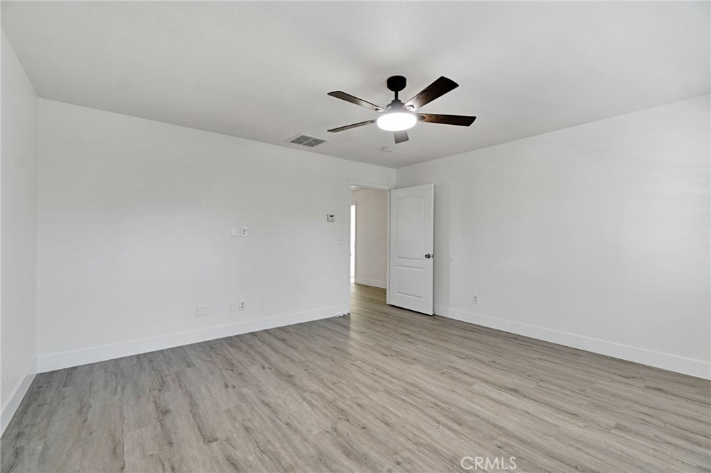 692 Blueberry Lane Madera, CA 93638 - Photo 30 of 44 an empty room with wooden floor and ceiling fan